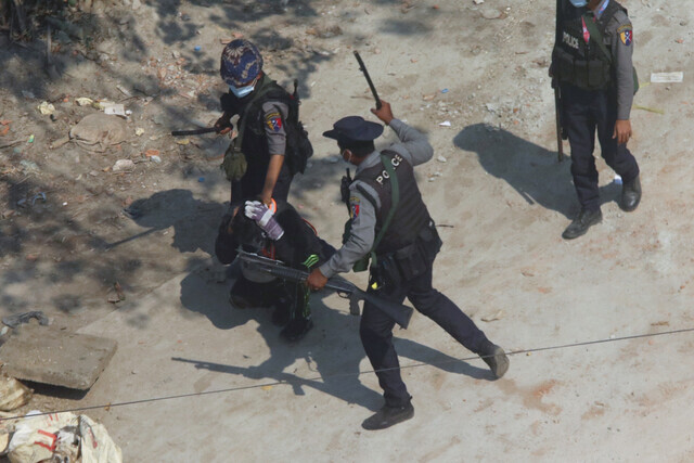 Riot police officers hold down a protester Saturday in a region on the outskirts of Yangon, Myanmar. (AP/Yonhap News)