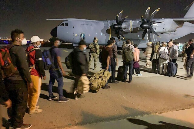 French and Afghan nationals line up to board a French military transport plane at the Kabul airport on Tuesday. (AFP/Yonhap News)