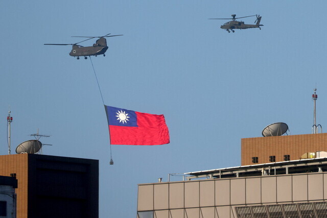 A military helicopter flies over Taiwan’s capital of Taipei on Tuesday, towing Taiwan’s national flag, as it rehearses for National Day celebrations that will be held on Sunday. (Reuters/Yonhap News)