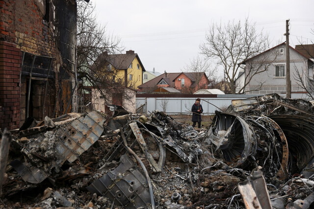 러시아가 우크라이나를 침공한 가운데, 25일 한 여성이 우크라이나 수도 키예프에서 폐허가 된 주택가를 걷고 있다. 키예프/로이터 연합뉴스