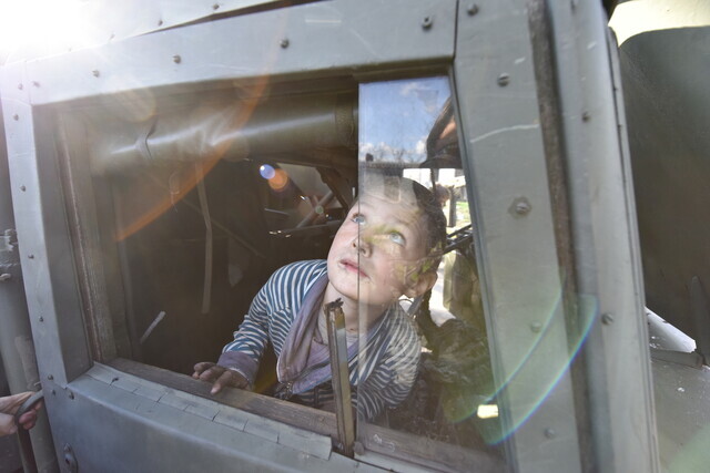 A child in a village in Chernihiv, Ukraine, looks toward the sky from a military truck left behind by Russian troops on April 27. (EPA/Yonhap News)