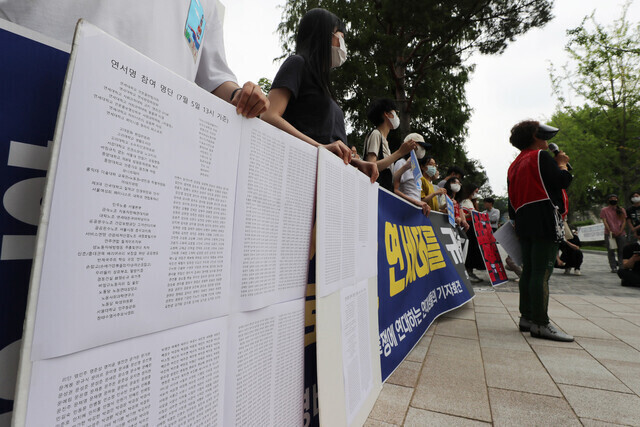 Yonsei University students and custodial and security staff hold a press conference on the Yonsei campus in Seoul on July 6, where they call for better working conditions for custodial and security staff. Those present hold up a collection of signatures in support of the Yonsei workers. (Shin So-young/The Hankyoreh)