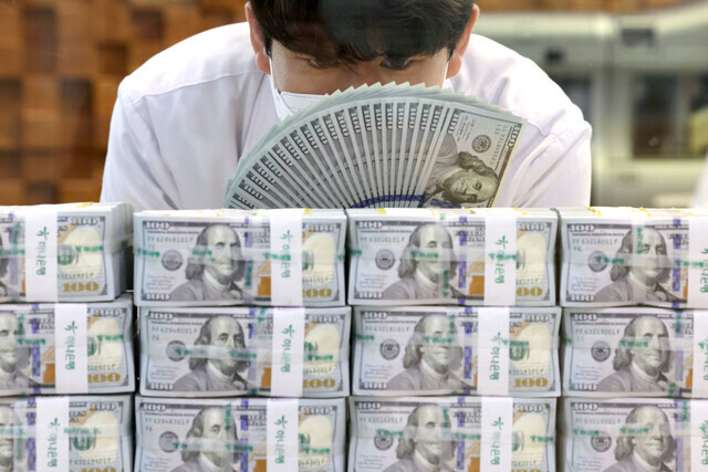 A Hana Bank employee counts dollars in this undated file photo. (Yonhap)