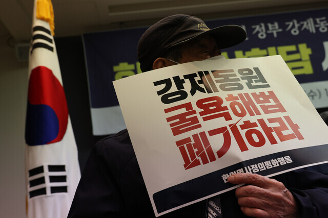A participant in a press conference organized by Joint Action for Historical Justice and Peaceful Korea-Japan Relations held at the Korea Press Center in downtown Seoul on March 15 holds up a sign reading “Scrap the humiliating solution to forced mobilization.” (Kim Hye-yun/The Hankyoreh)