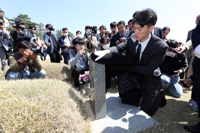 Chun Woo-won, the grandson of the late dictator Chun Doo-hwan, wipes down the gravestone for Kim Kyeong-cheol, a martyr of the democratic uprising that was brutally quashed by Chun Doo-hwan in May 1980 in Gwangju, during a visit to the May 18th National Cemetery on March 31. (Yonhap)
