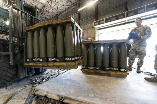 A US soldier watches as 155mm artillery shells are moved at an airbase in Delaware on April 29, 2022. (AP/Yonhap)