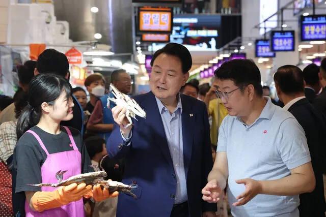 President Yoon Suk-yeol of South Korea holds up an Asian blue crab while talking to a merchant at Noryangjin Fish Market in Seoul on Aug. 31. (courtesy of the presidential office)