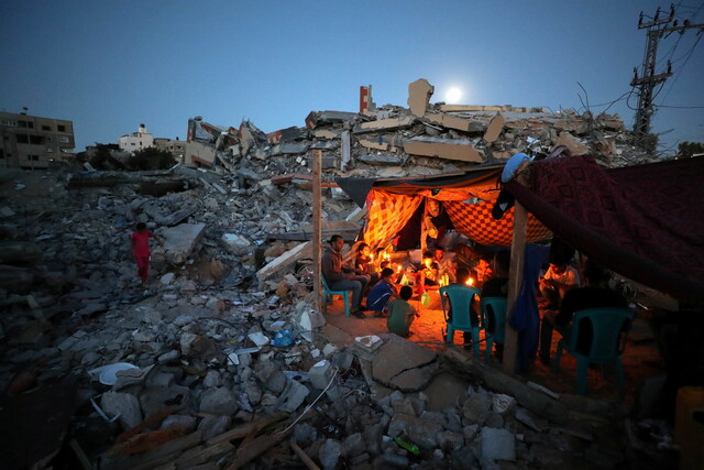 2021년 5월25일 팔레스타인 땅 가자지구에서 한 가족이 이스라엘군의 폭격으로 무너진 집터에서 간이천막을 치고 촛불을 밝히고 있다. REUTERS