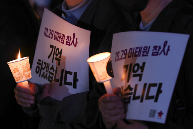 Participants in a memorial mass by the group Catholic Priests’ Association for Justice put on on Oct 30 for the one-year anniversary of the deadly Itaewon crowd crush disaster hold candles and signs reading “Oct. 29 Itaewon disaster, We will remember.” (Yonhap)