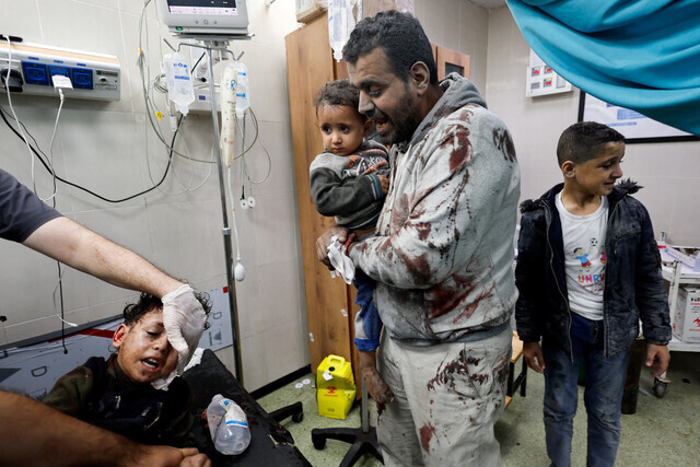 A man injured in an Israeli bombing holds a child at Nasser Hospital in Gaza’s n Khan Younis on Nov. 13. (Reuters/Yonhap)