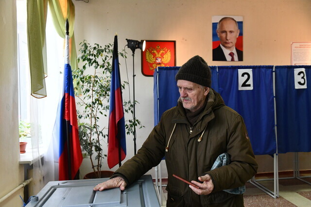 A man places his vote in the ballot box at a polling station in Donetsk, in Russian-occupied Ukraine, on March 17, 2024. (EPA/Yonhap)