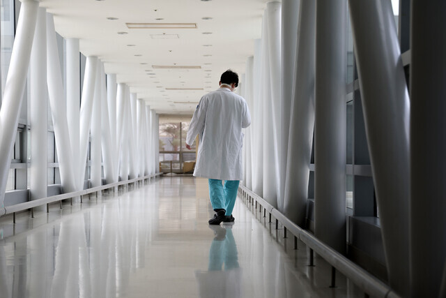 A person in scrubs walks down an otherwise empty hallway at a major university hospital in Seoul on March 24, 2024. (Yonhap)