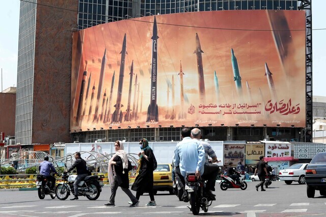 People walk through Tehran, Iran, on April 2, 2024, where a mural of Iranian missiles hangs off a building. (AFP/Yonhap)