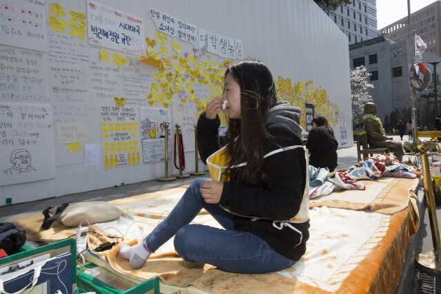 University student Choi Hye-ran wipes her nose during a sit-in protest next to the comfort woman statue in front of the Japanese Embassy in Seoul