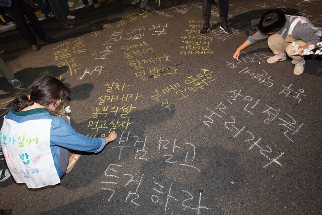 10월1일 서울 대학로에서 열린 ‘백남기 농민 추모대회’에 참석한 사람들이 진상 규명을 요구하고 부검에 반대하는 내용의 글씨를 바닥에 적고 있다. 박승화 기자