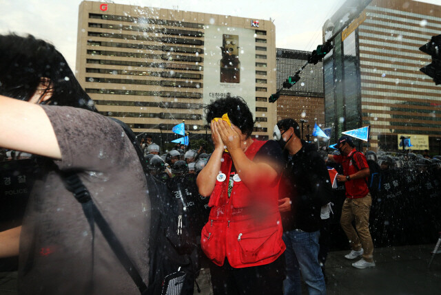 One protester wipes her face after being sprayed with a police water cannon mixed with capsaicin at a rally opposing the government’s plans to reform the labor market at Gwanghwamun Square in central Seoul