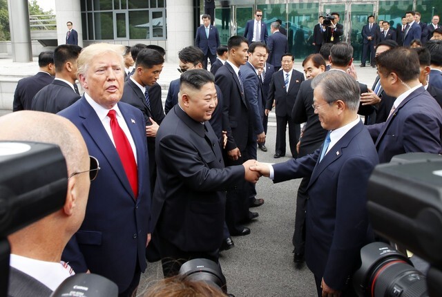 South Korean President Moon Jae-in and North Korean leader Kim Jong-un shake hands next to US President Donald Trump at Panmunjom on June 30. (Kim Jung-hyo