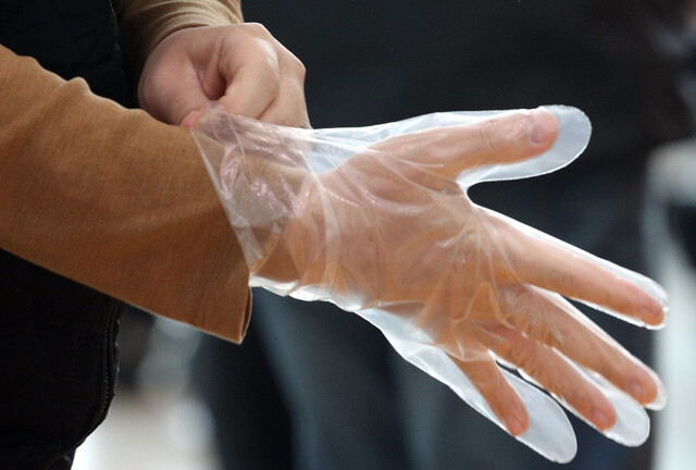 A voter at a polling station in Seoul puts on disposable gloves ahead of early voting on Apr. 10. (Kim Bong-gyu, staff photographer)