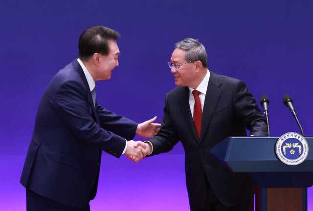 President Yoon Suk-yeol of South Korea shakes hands with Chinese Premier Li Qiang after the latter’s remarks at a joint press conference held after a trilateral summit with Japan at the Blue House in Seoul on May 27, 2024. (Yonhap)