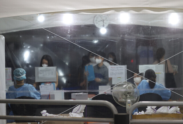 People wait in line at a temporary screening center in Seoul to get tested for COVID-19 on Tuesday. (Yonhap News)