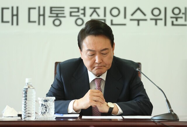 President-elect Yoon Suk-yeol reads over materials during a meeting of the presidential transition committee subcommittee leaders held at their office in Seoul’s Tongui neighborhood on March 22. (Yonhap News)