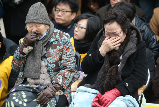 Former comfort women Gil Won-ok (left) and Lee Yong-soo cry while listening to attendees’ remarks at this year’s last weekly demonstration in support of the comfort women in front of the Japanese embassy in Seoul’s Jongno district