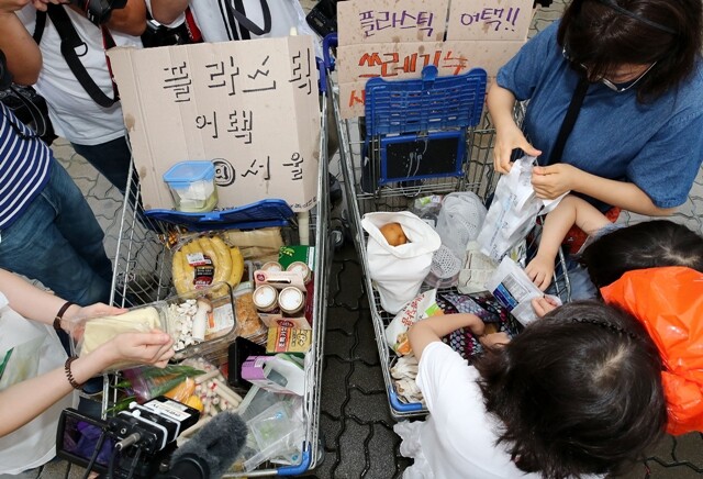한 대형마트에서 열린 ‘플라스틱 어택’ 행사에서 참가자들이 마트에서 구입한 물건의 포장지를 벗기고 있다. 연합뉴스