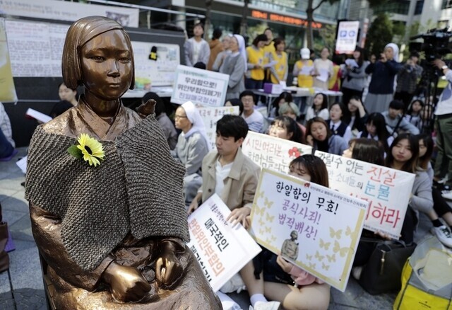 Protesters calling for reparations for victims of the “comfort women” system of sexual slavery employed by the Japanese military sit around the Statue of Peace memorial to comfort women outside the former Japanese Embassy in Seoul’s Jongno District. (Kim Myoung-jin/The Hankyoreh)