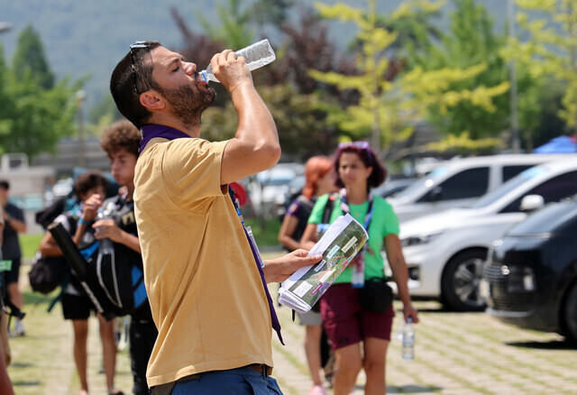 A participant in the 2023 World Scout Jamboree in Saemangeum takes a sip of water amid a heat wave warning in effect in the area. (Yonhap)
