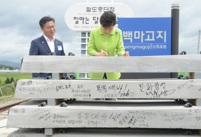 South Korean President Park Geun-hye writes a message for unification on a concrete sleeper at the big groundbreaking ceremony for the southern section of the Gyeongwon train line