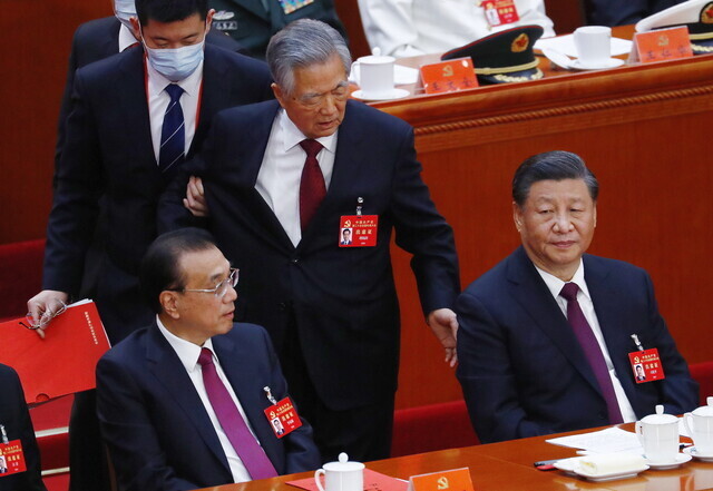 Hu Jintao, the former leader of China who had been sitting beside Xi Jinping during the party congress, appears to speak to Xi while being escorted out of the hall. (EPA/Yonhap)