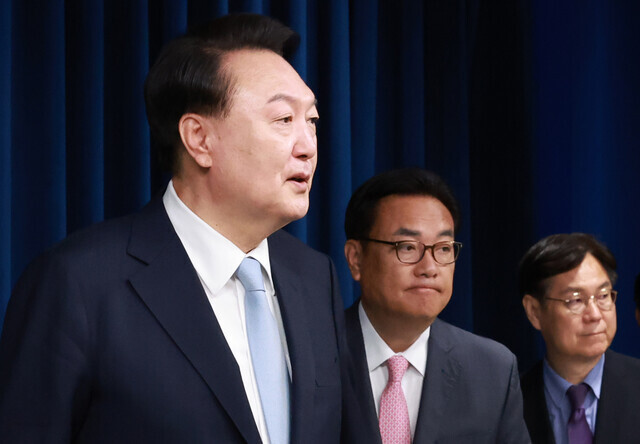 President Yoon Suk-yeol (left) stands with his newly appointed chief of staff, Chung Jin-suk (center), and his former chief of staff, Lee Kwan-sup, as he announces a personnel reshuffle at the presidential office on April 22, 2024. (Yonhap)