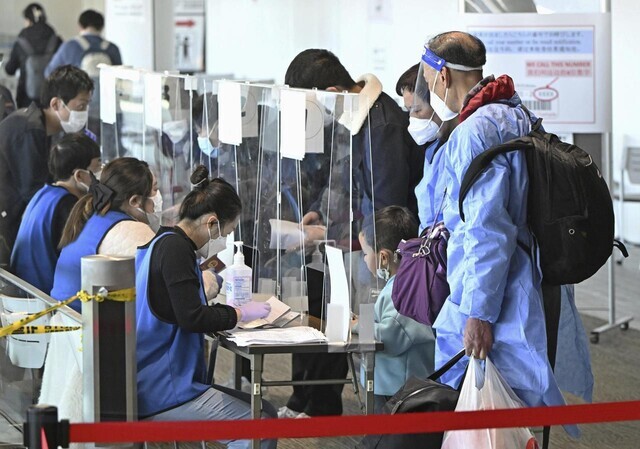 Staff at Tokyo’s Narita International Airport check the proof of negative COVID-19 test documents of travelers from Shanghai on Jan. 8. (Kyodo News/Yonhap)