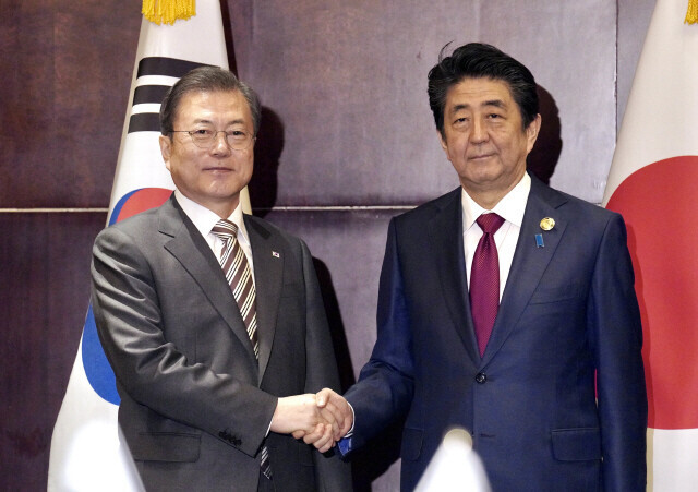 President Moon Jae-in shakes hands with then-Japanese Prime Minister Shinzo Abe while in Sichuan, China, in December 2019. (Blue House pool photo)