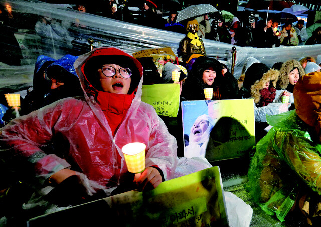 University students who are members of the Peace Butterfly Network and other organizations express opposition to the removal of the statue and call for renegotiation of the recent comfort women settlement and for the Japanese government to acknowledge its legal responsibility during a candlelight vigil