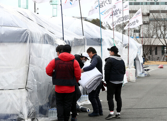 Striking workers with the Cargo Truckers Solidarity Division head into their sit-in tent in the parking lot of an inland container depot in Uiwang, Gyeonggi Province, on Dec. 4 with blankets due to a cold snap. (Yoon Woon-sik/The Hankyoreh)