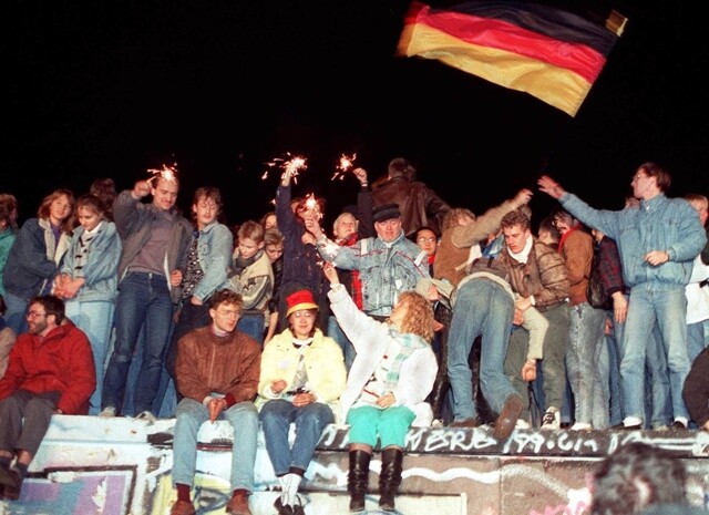 1989년 11월10일 무너진 베를린장벽 위에서 독일인들이 폭죽을 터뜨리고 깃발을 흔들며 축하하고 있다. EPA 연합