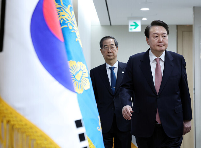 President Yoon Suk-yeol heads into a Cabinet meeting at the presidential office in Seoul on March 21 flanked by Prime Minister Han Duck-soo. (Yonhap)