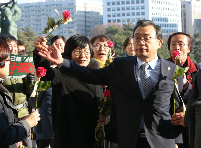 이정현 새누리당 대표가 12월9일 국회 본청 계단 앞에서 시민단체 회원이 건네는 장미꽃을 뿌리치고 있다.
