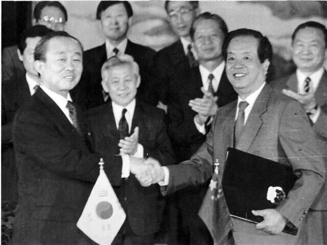 South Korean Foreign Minister Lee Sang-ok and Chinese Minister of Foreign Affairs Qian Qichen shake hands on Aug. 24, 1992, after signing a joint communique establishing diplomatic ties between their two nations. (Hankyoreh file photo)