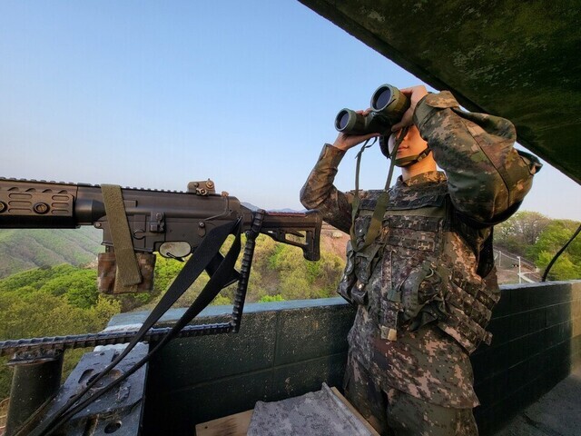 A soldier with South Korea’s 7th Infantry Division uses binoculars from his perch in a general outpost (GOP) in the summer of 2023. (courtesy of the ROK Army)