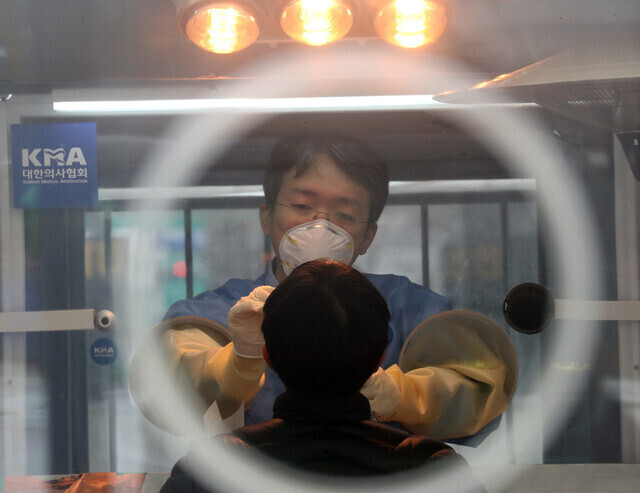 A health worker conducts a COVID-19 test on a man at a temporary screening center in Seoul Plaza. (Yonhap News)