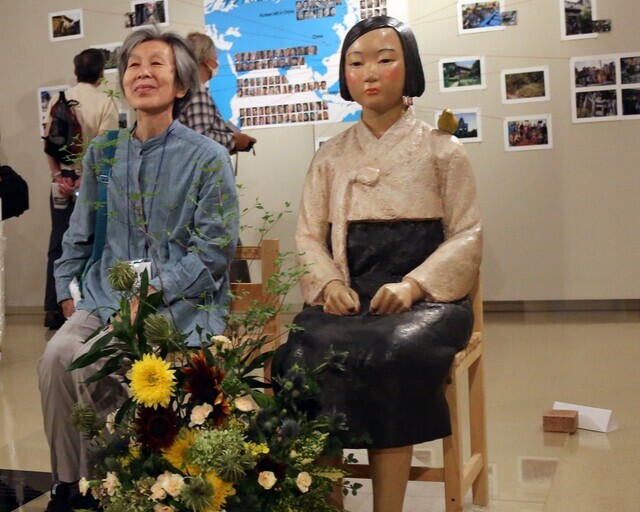 A visitor sits next to a comfort woman statue at an art exhibition titled “After ‘Freedom of Expression?’” at Citizen’s Gallery Sakae, a public facility in Nagoya, Aichi Prefecture. The exhibition was suspended just three days after it opened. (Yonhap News)