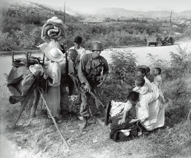 ❹ 한 미군 병사가 대전 함락을 피해 도망친 한국인 여성을 도우려 멈추었다. 1950년 7월21일 촬영.