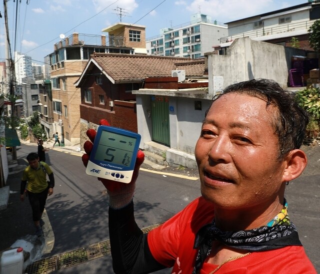 지난해 8월1일 서울 주택가에서 한 이삿짐센터 노동자가 51.2도를 기록한 온도계를 들어 보이고 있다(올해 시민모니터링에 사용될 온도기록계는 아님). 류우종 기자