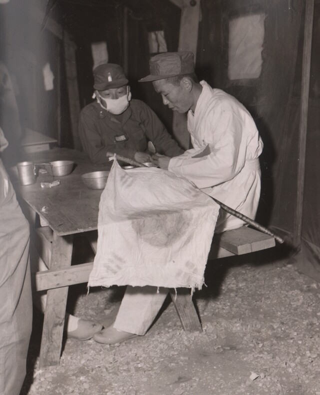 ❷ 포로 교환 협정에 따라 송환되는 국군 포로가 제5국군 이동외과병원 본부에서 직접 만든 깃발을 옆에 두고 천천히 뜨거운 수프를 먹고 있다. 1953년 4월25일. 전갑생 제공