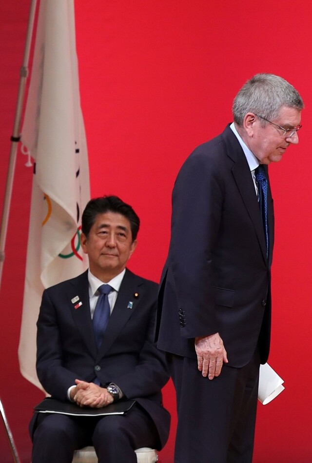 도쿄올림픽을 1년 앞둔 7월24일, 토마스 바흐 국제올림픽위원회 위원장이 연설을 위해 아베 신조 총리 앞을 지나가고 있다. AFP 연합뉴스
