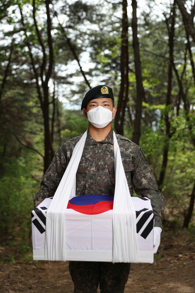 A South Korean soldier holds exhumed remains from the Korean War in preparation for them to be transported to a temporary place of interment after holding a funeral ceremony on a mountain in Gangwon Province’s Hongcheon County on April 28. (Kim Bong-gyu/The Hankyoreh)