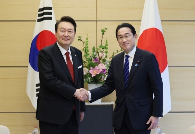 President Yoon Suk-yeol of South Korea (left) shakes hands with Prime Minister Fumio Kishida of Japan in Tokyo on March 16. (Yonhap)