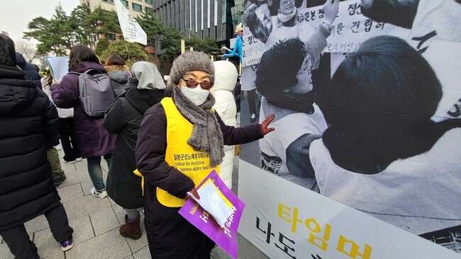 Yoon Young-ae takes part in Wednesday’s demonstration calling for the Japanese government to redress the victims of wartime sexual slavery, and points to a photo of herself at the first-ever Wednesday Demonstration held in January 1992. (Park Ji-young/The Hankyoreh)